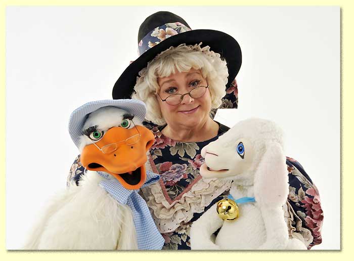 Photo of Mother Goose with a lamb puppet and a goose puppet.