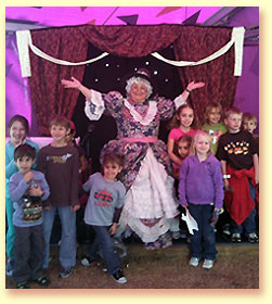 Photograph of Mother Goose with lots of children gathered around her at the State Fair of Texas.
